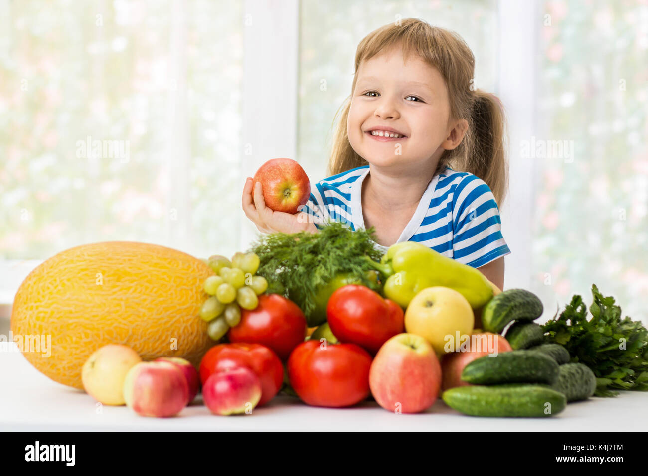 Felice bambina e un sacco di frutta e verdura. concetto di alimenti sani. Foto Stock