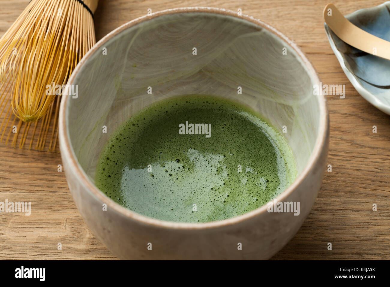 La preparazione di una tazza di tè matcha con una frusta di tè Foto Stock