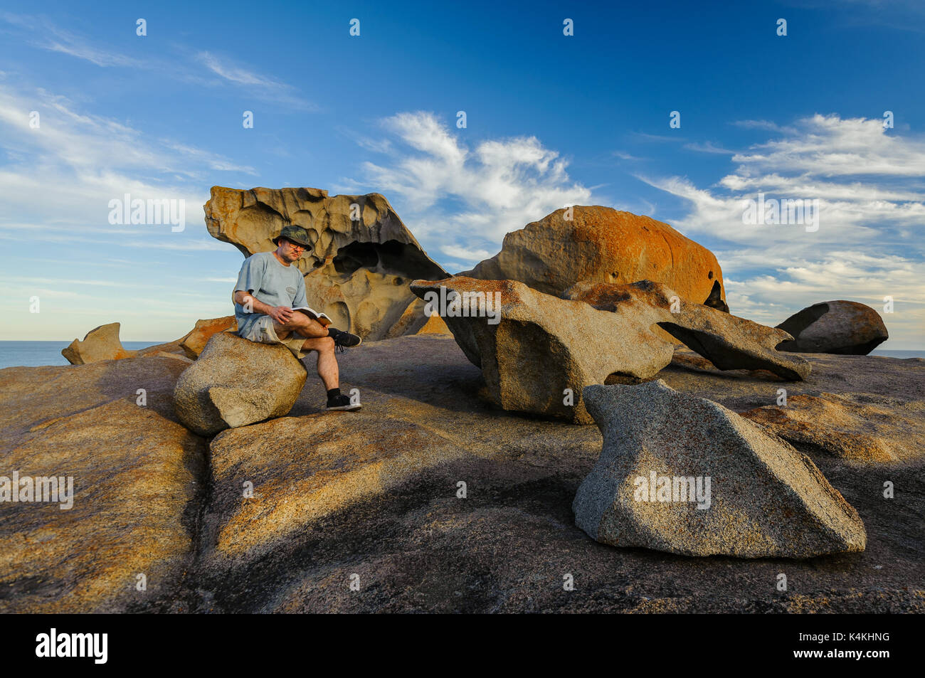 Persona seduta su un sedile di roccia a Remarkable Rocks. Foto Stock
