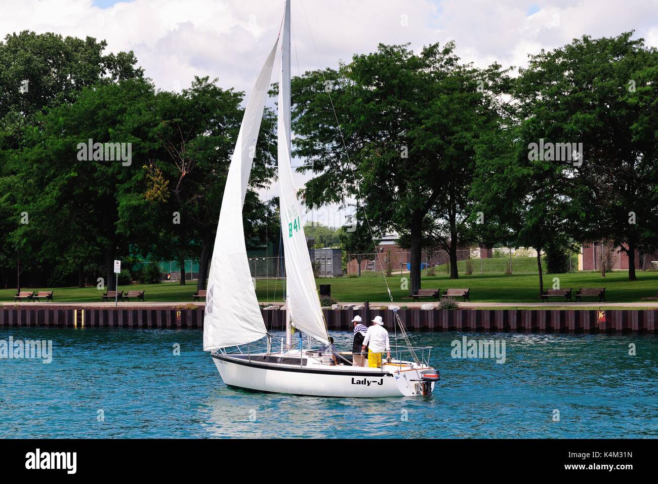 Un lone sailboat rendendo il suo modo dal Lago Michigan in un canale che conduce a Waukegan Harbour su una mattina d'estate. Waukegan, Illinois, Stati Uniti d'America. Foto Stock