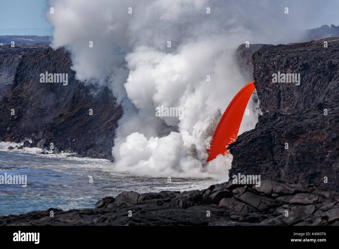 Vista ingrandita del rosso di lava fusa di un vulcano attivo da una cima in Hawaii National Park che scorre come un fuoco flessibile nell'esplosione di ocea Foto Stock