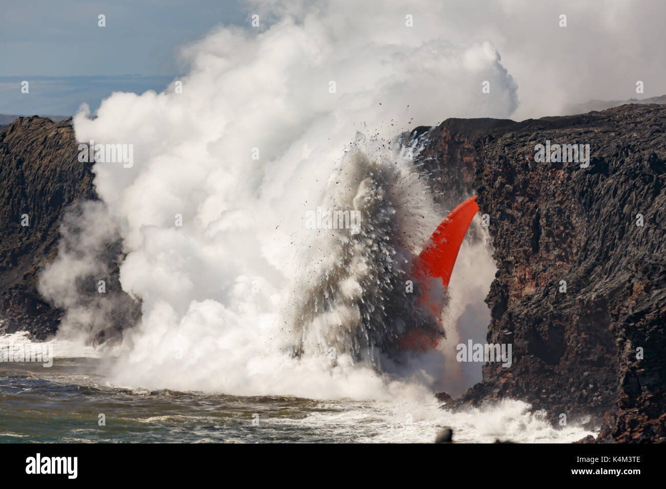 Vista ingrandita del rosso di lava fusa di un vulcano attivo su una cima in hawaii national park scorre come un tubo antincendio nell'oceano che esplodono Foto Stock
