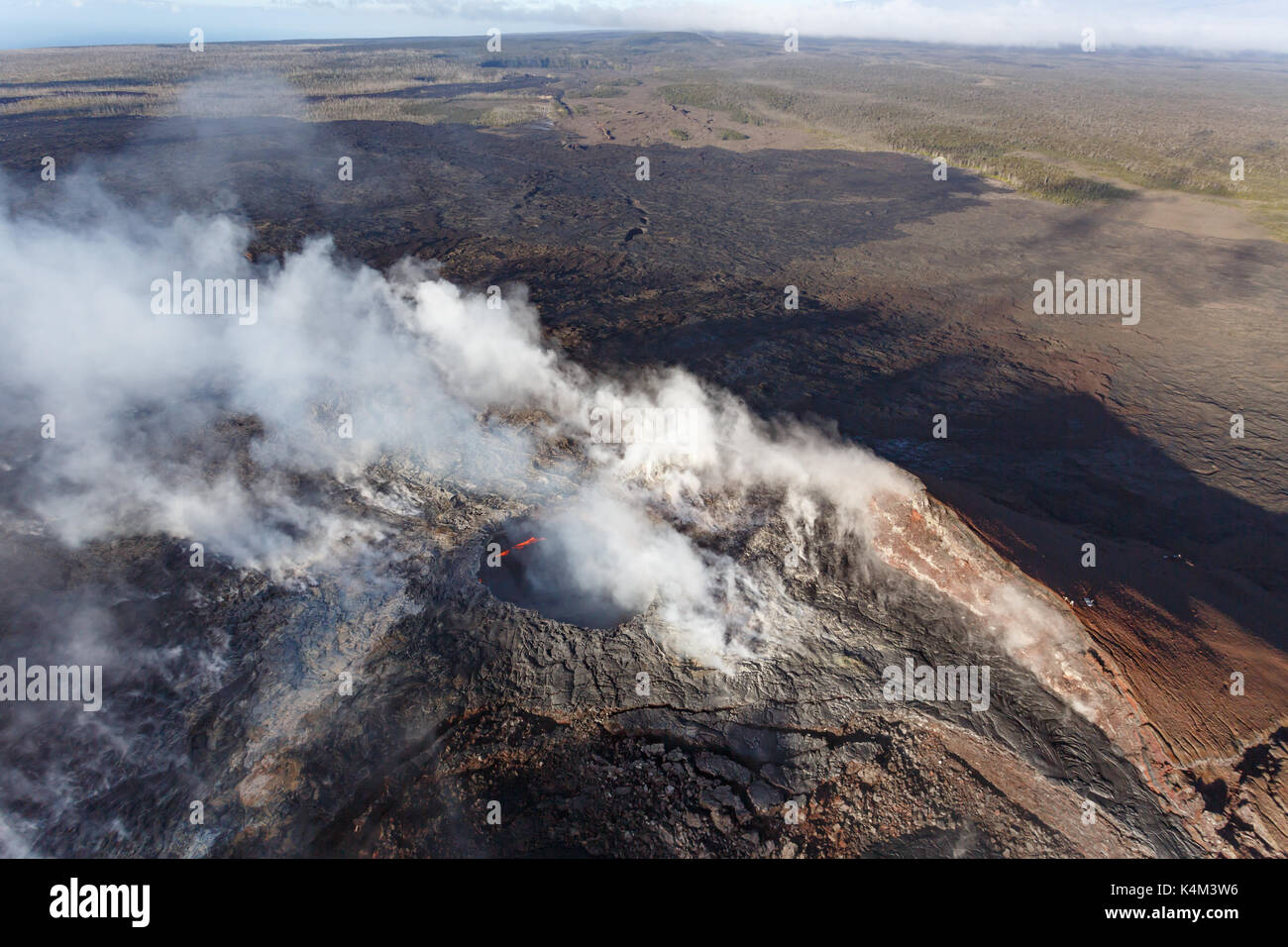 Vista aerea del fumo caldera e rosso di lava fusa di un vulcano attivo su una cima in Hawaii Foto Stock