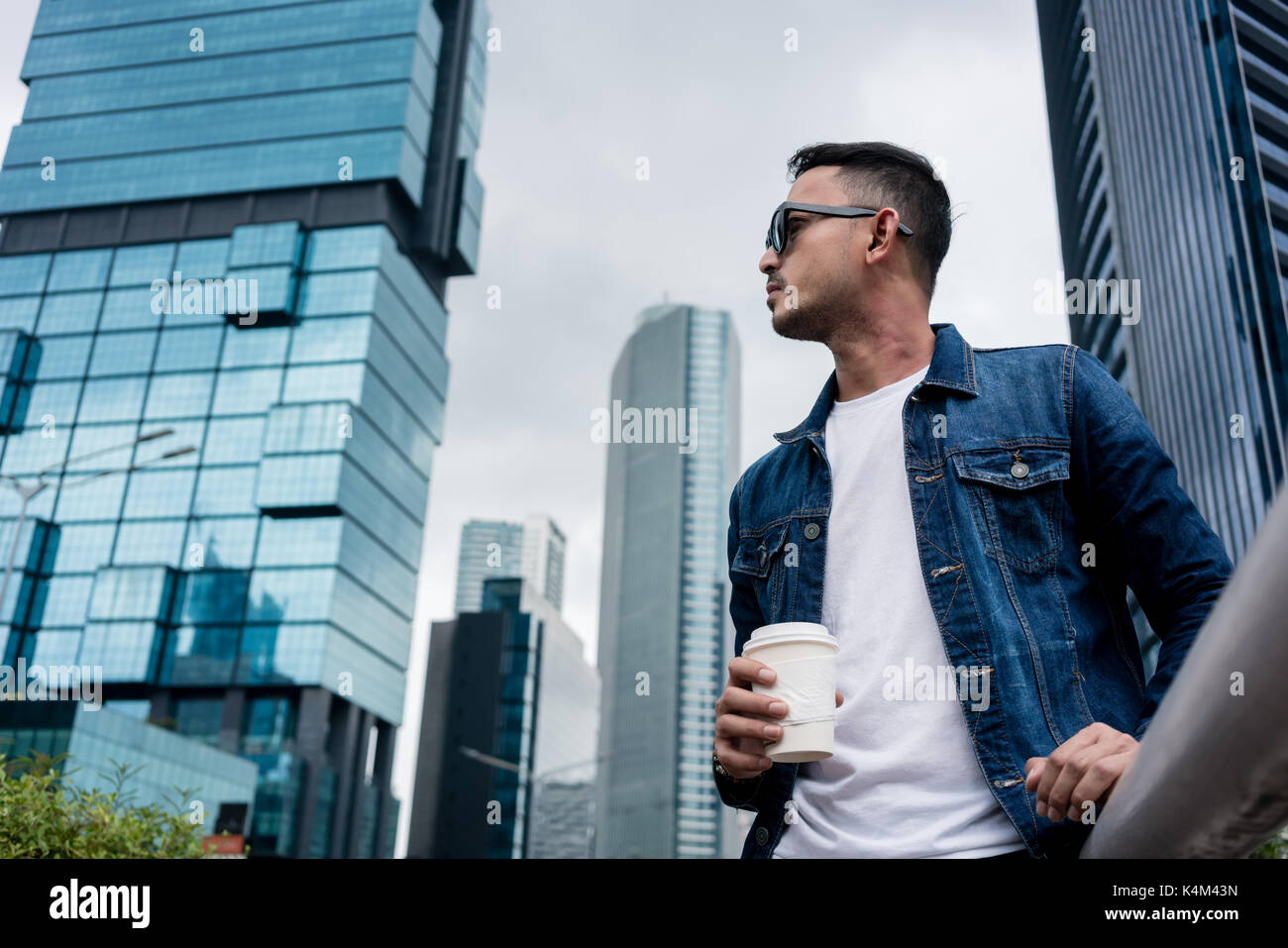 Giovane uomo che indossa blu denim camicia mentre fantasticando all'aperto ho Foto Stock