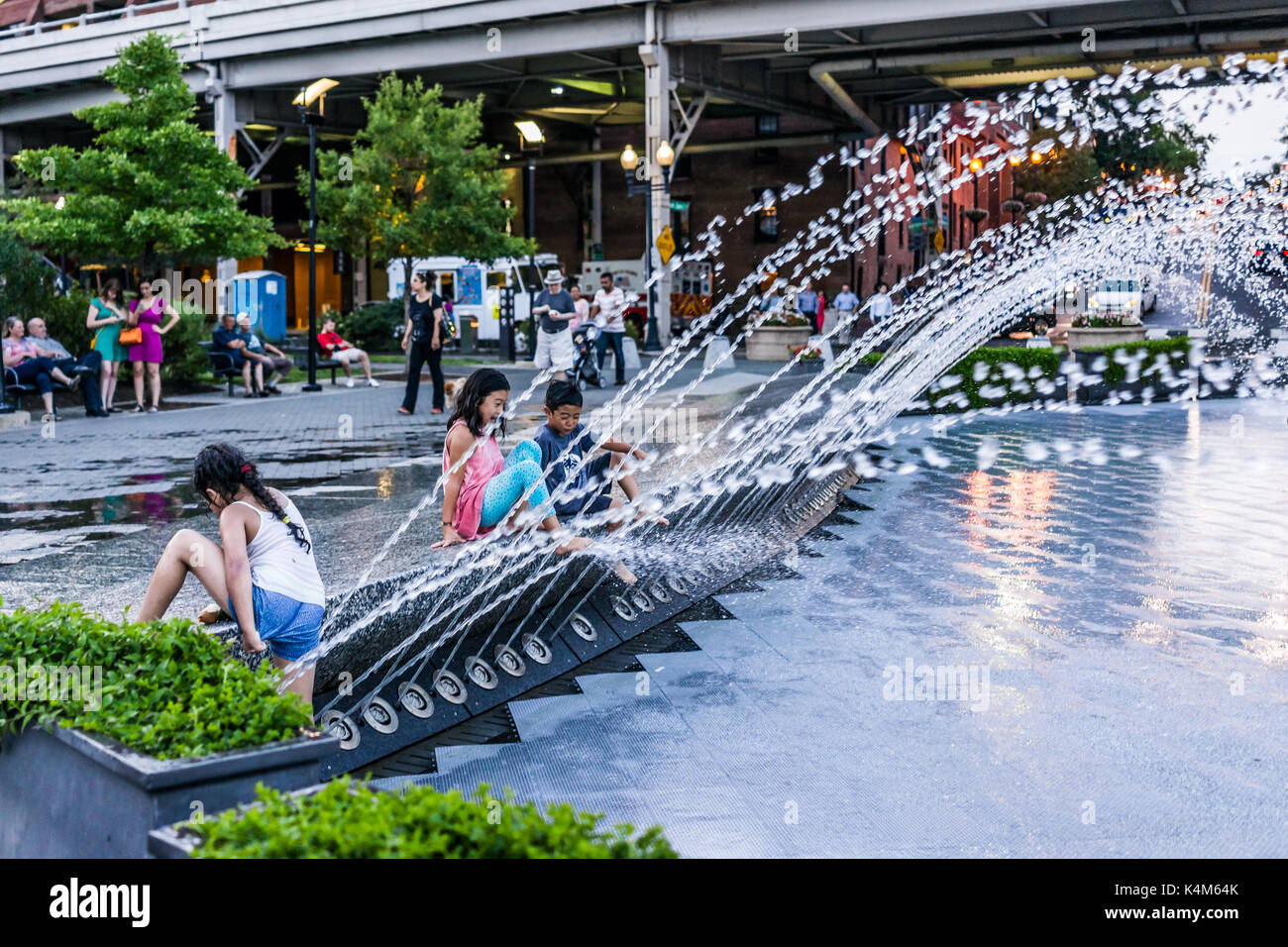 Washington DC, Stati Uniti d'America - 4 Agosto 2017: giovani bambini che giocano in acqua Fontana nel parco di Georgetown in serata con spruzzi d'acqua Foto Stock