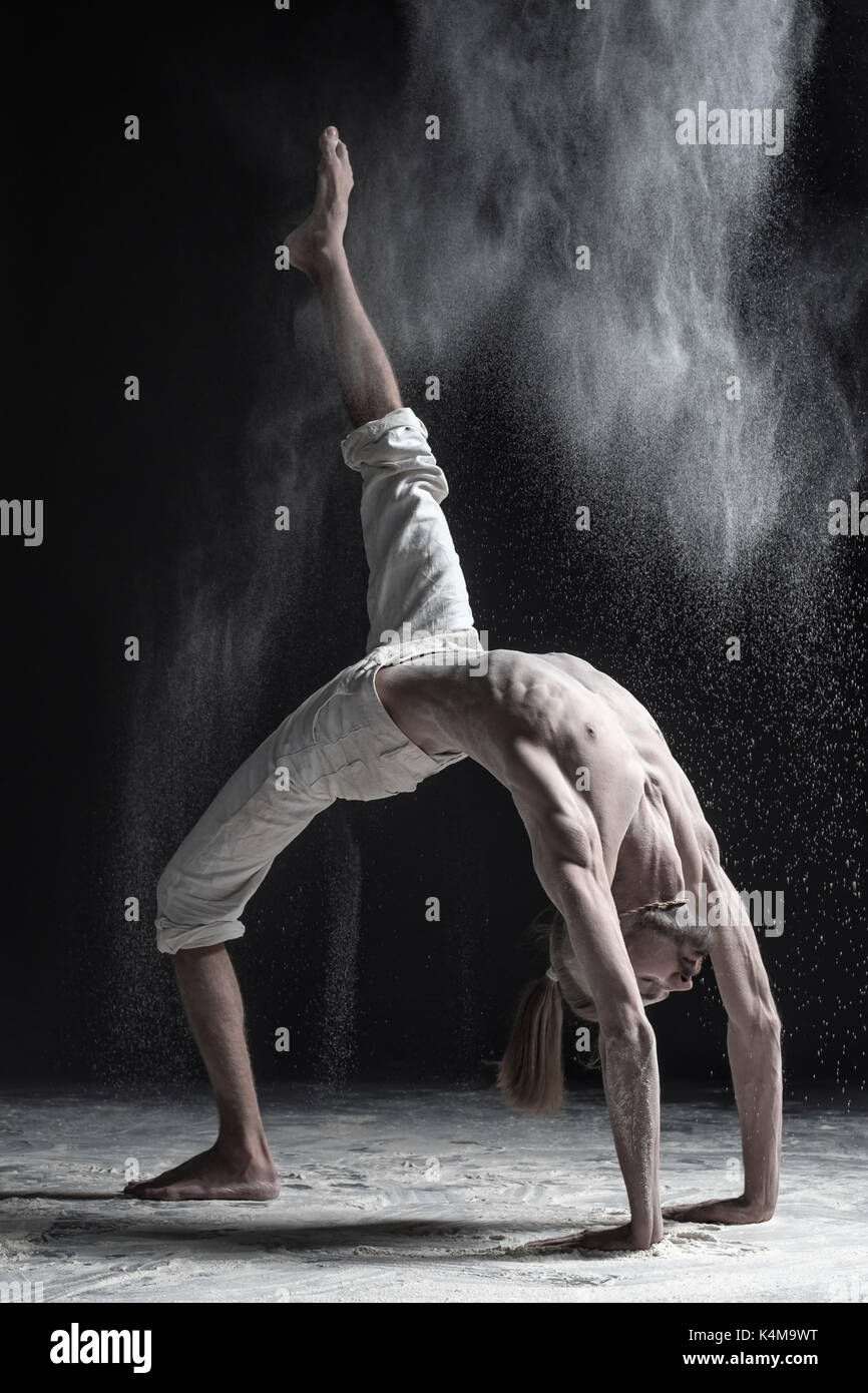 Vista laterale di caucaisanl giovane uomo che lavora fuori, fare yoga o pilates esercizio. ponte pongono, urdhva dhanurasana. Foto Stock