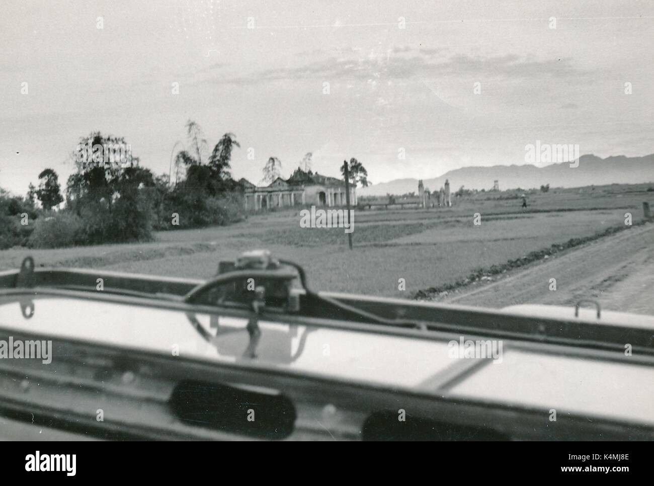 Una grande casa accanto a una strada è visto da sopra il cruscotto di un veicolo militare, con un piccolo figurine visibile sul cruscotto, durante la guerra del Vietnam, 1968. Foto Stock
