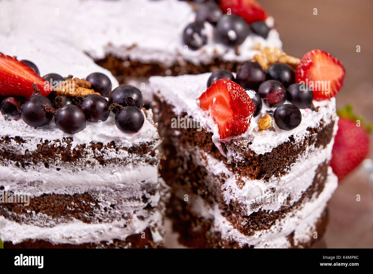 Un taglio della torta con la panna montata e frutti di fragola sulla tavola di legno Foto Stock