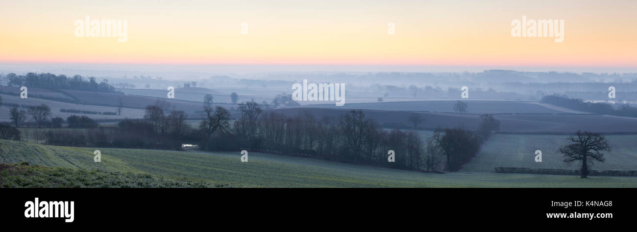 Il bagliore rosa del tramonto su un effetto smerigliato e nebbioso Northamptonshire paesaggio guardando verso Northampton è avvolta nella nebbia all'orizzonte, Inghilterra. Foto Stock