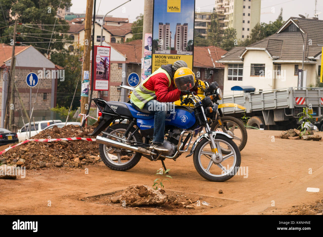 Boda boda motociclo taxi driver in attesa sul veicolo dal lato della strada, Nairobi, Kenia Foto Stock