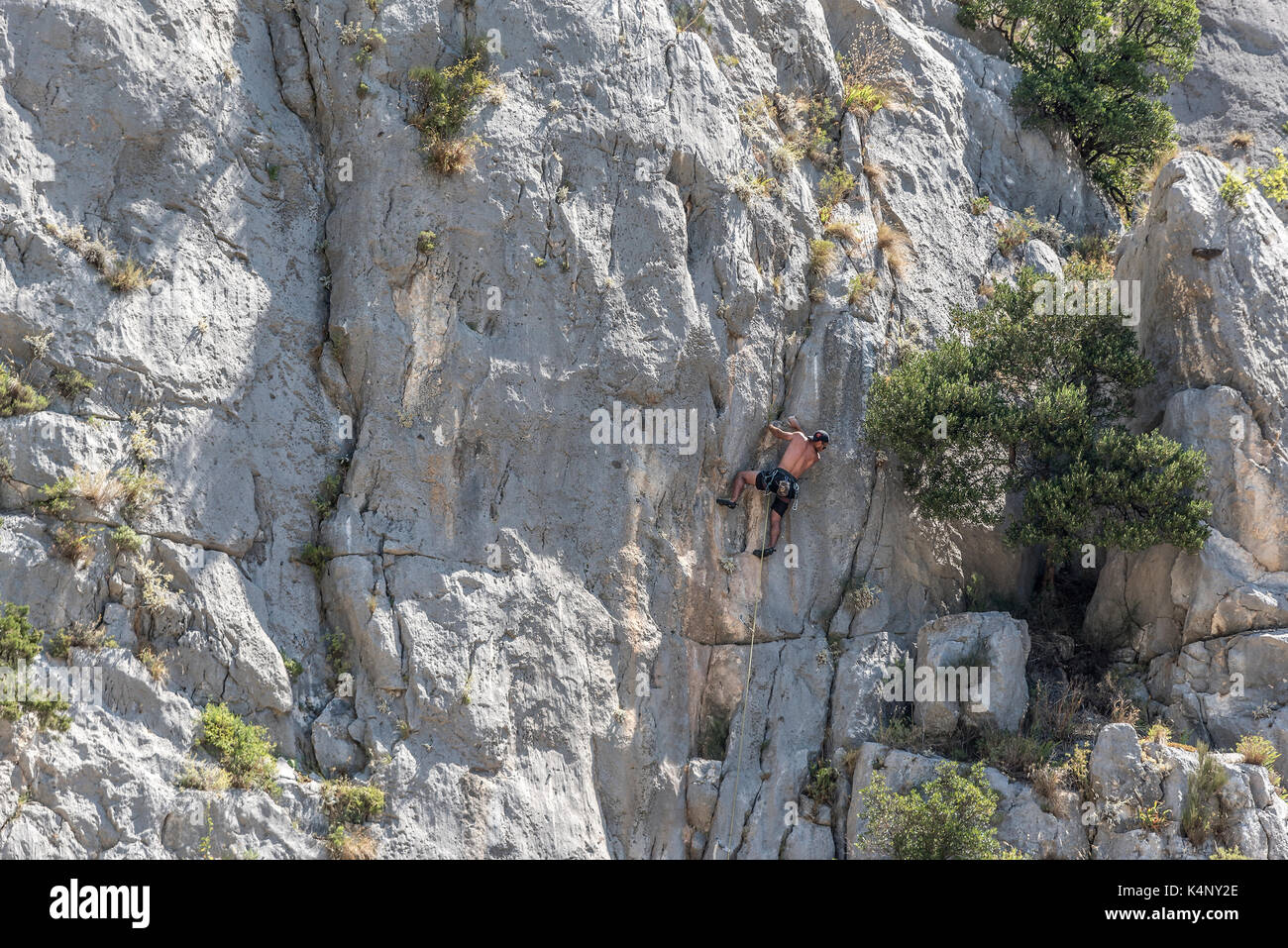 Un giovane scalatore si sale la parete a strapiombo. Foto Stock