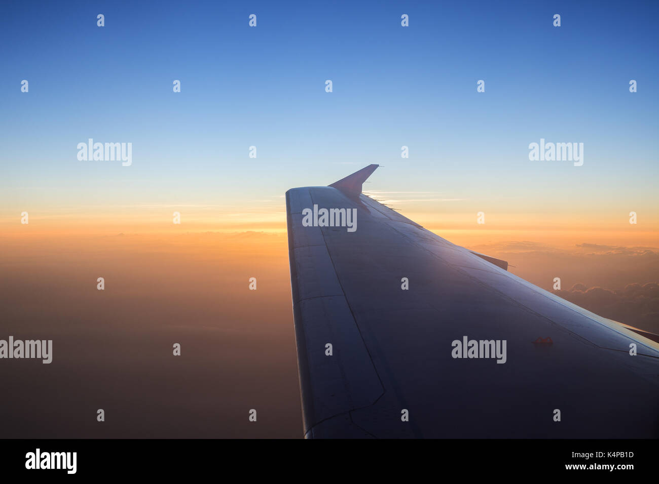 Vista di orangle cielo nuvoloso e ala di aeroplano a sunrise. copia di spazio. Foto Stock