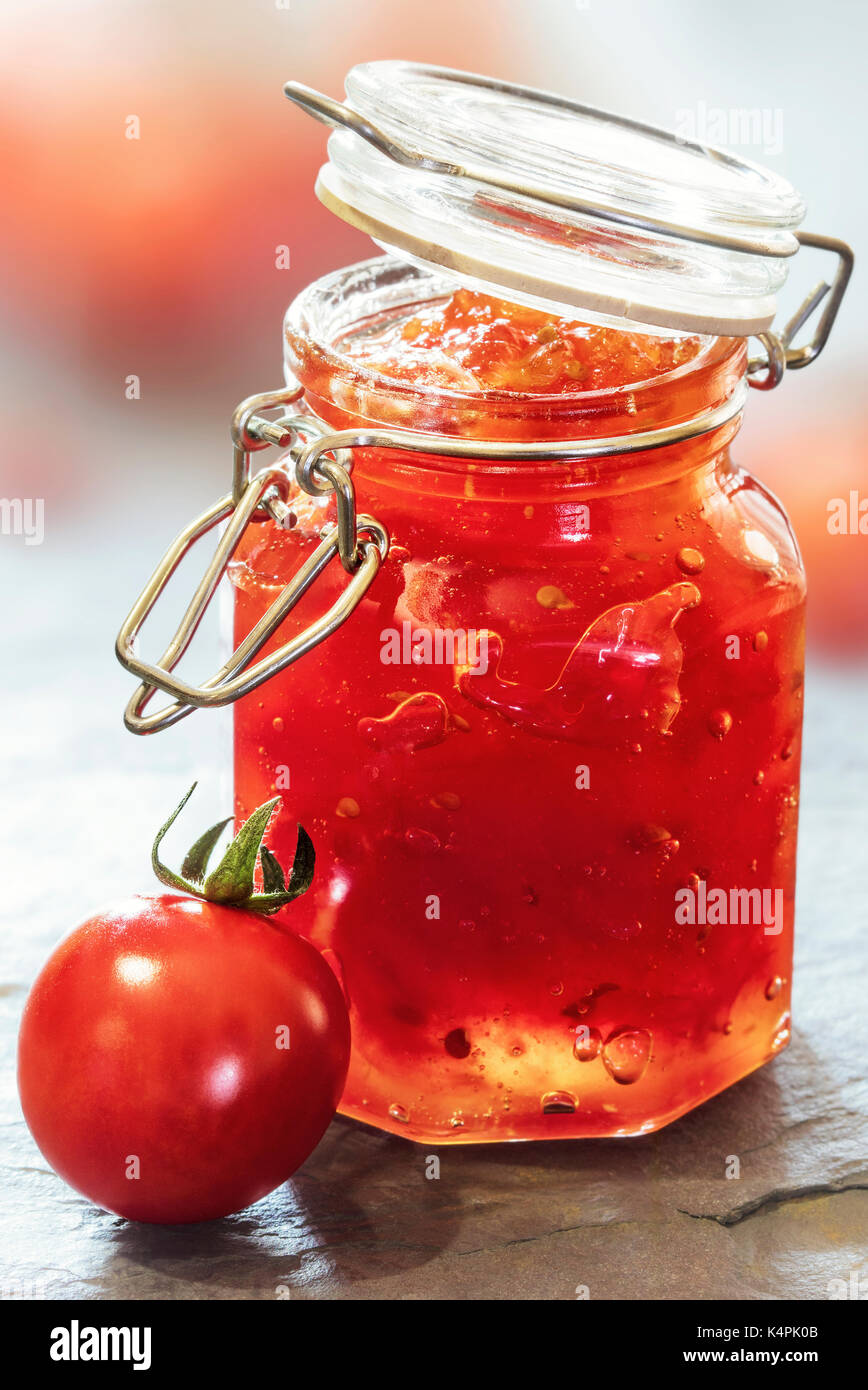 Pomodoro marmellata in un barattolo di vetro su una tavola di ardesia top Foto Stock