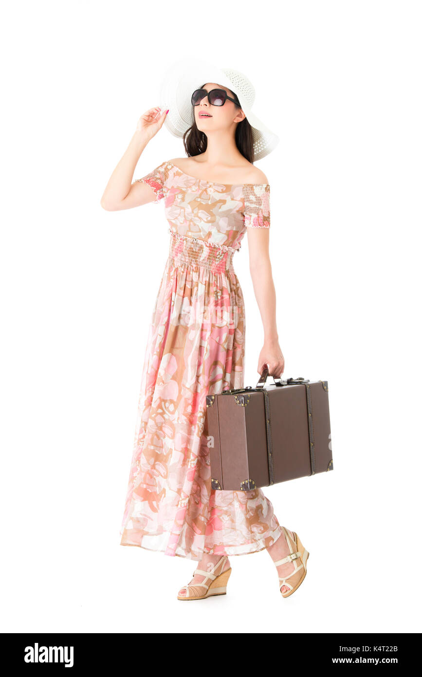 Elegante giovane donna traveler isolati su sfondo bianco e indossano abiti lunghi trasporto bagaglio vintage valigia pensando per la pianificazione del viaggio. Foto Stock