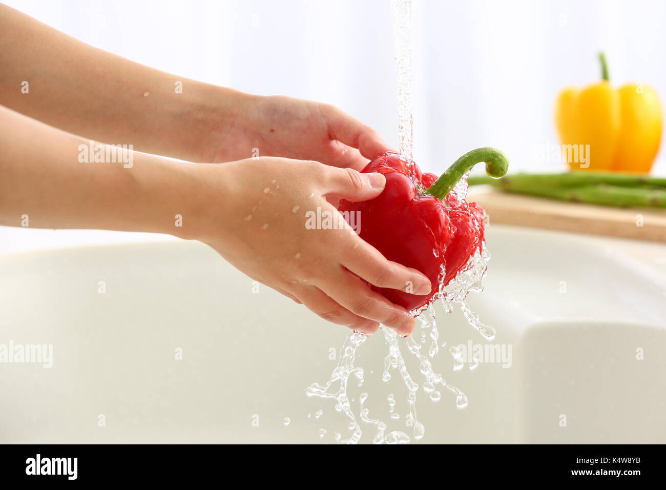 Donna giapponese il lavaggio della verdura in cucina Foto Stock