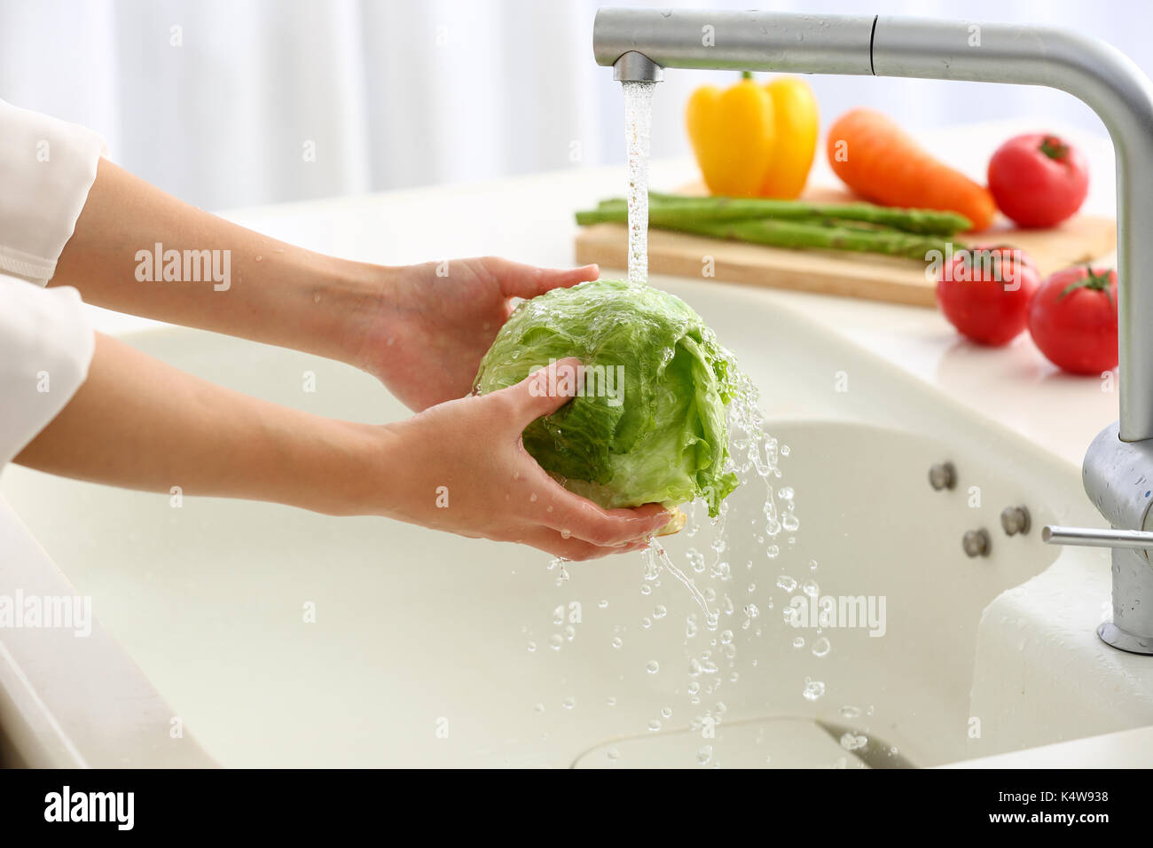 Donna giapponese il lavaggio della verdura in cucina Foto Stock
