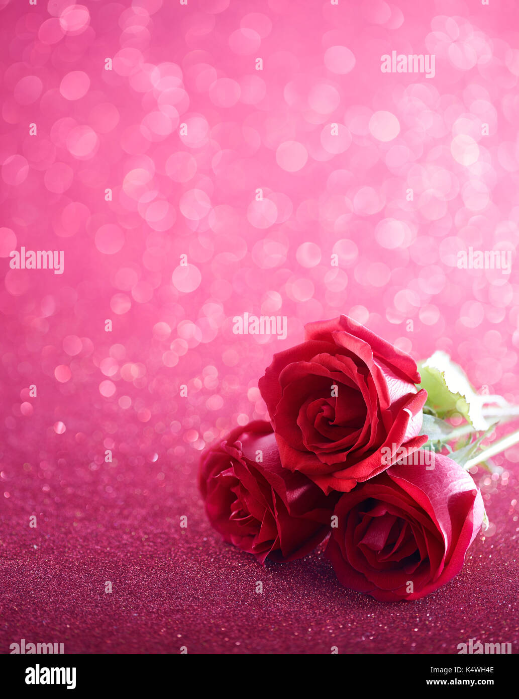 Tre rose rosse su rosa sfondo scintillante Foto Stock