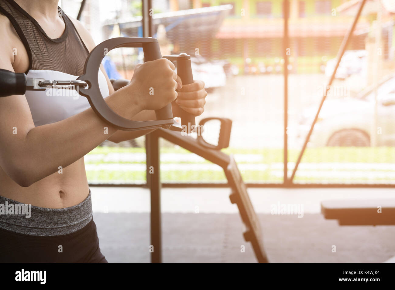 Giovane donna esecuzione di esercizio con la macchina nel centro fitness. atleta femminile la pompa muscolo con cavo crossover in palestra. sporty ragazza asiatica che lavora fuori Foto Stock