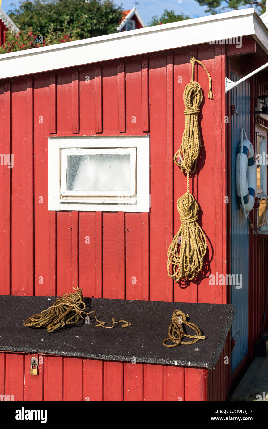 Materiale naturale fasci di corda appesa sul rosso parete in legno e giacente sul coperchio. Foto Stock