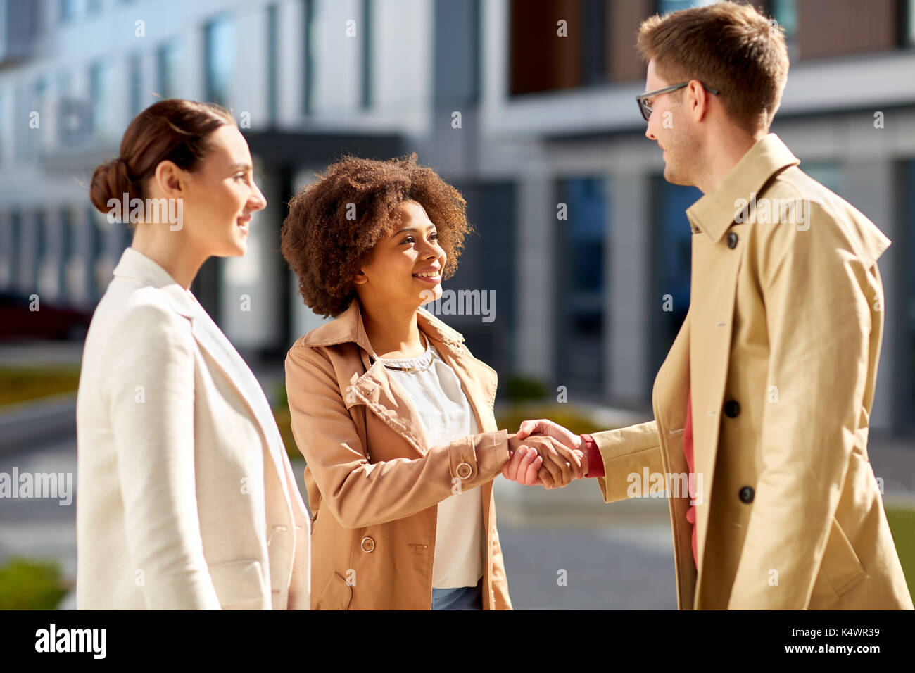 Le persone felici si stringono la mano su una strada di città Foto Stock