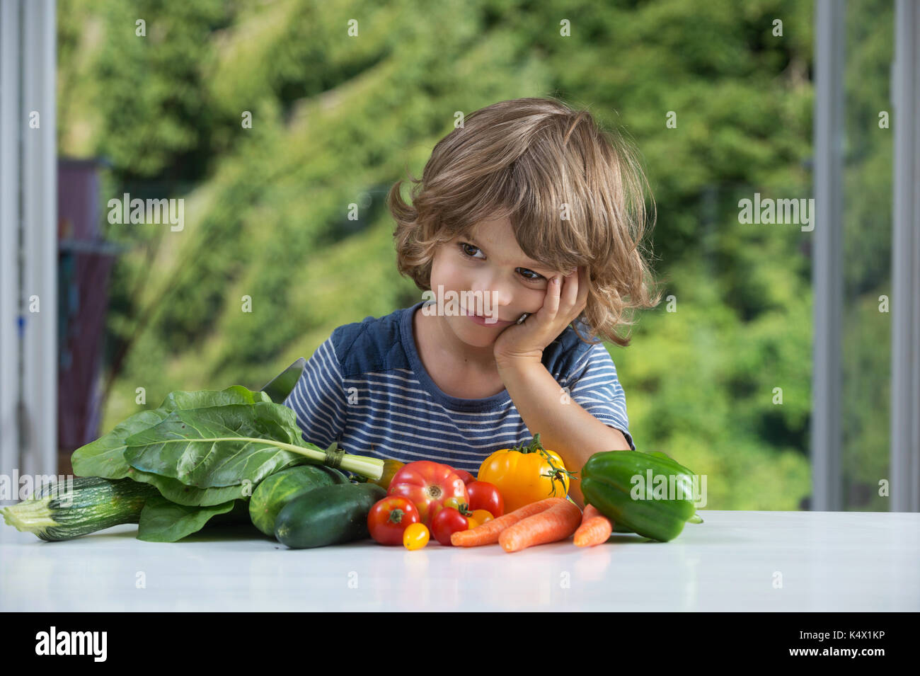 Carino piccolo ragazzo seduto al tavolo entusiasti di farine vegetali, bene o male abitudini alimentari, nutrizione e alimentazione sana nozione Foto Stock