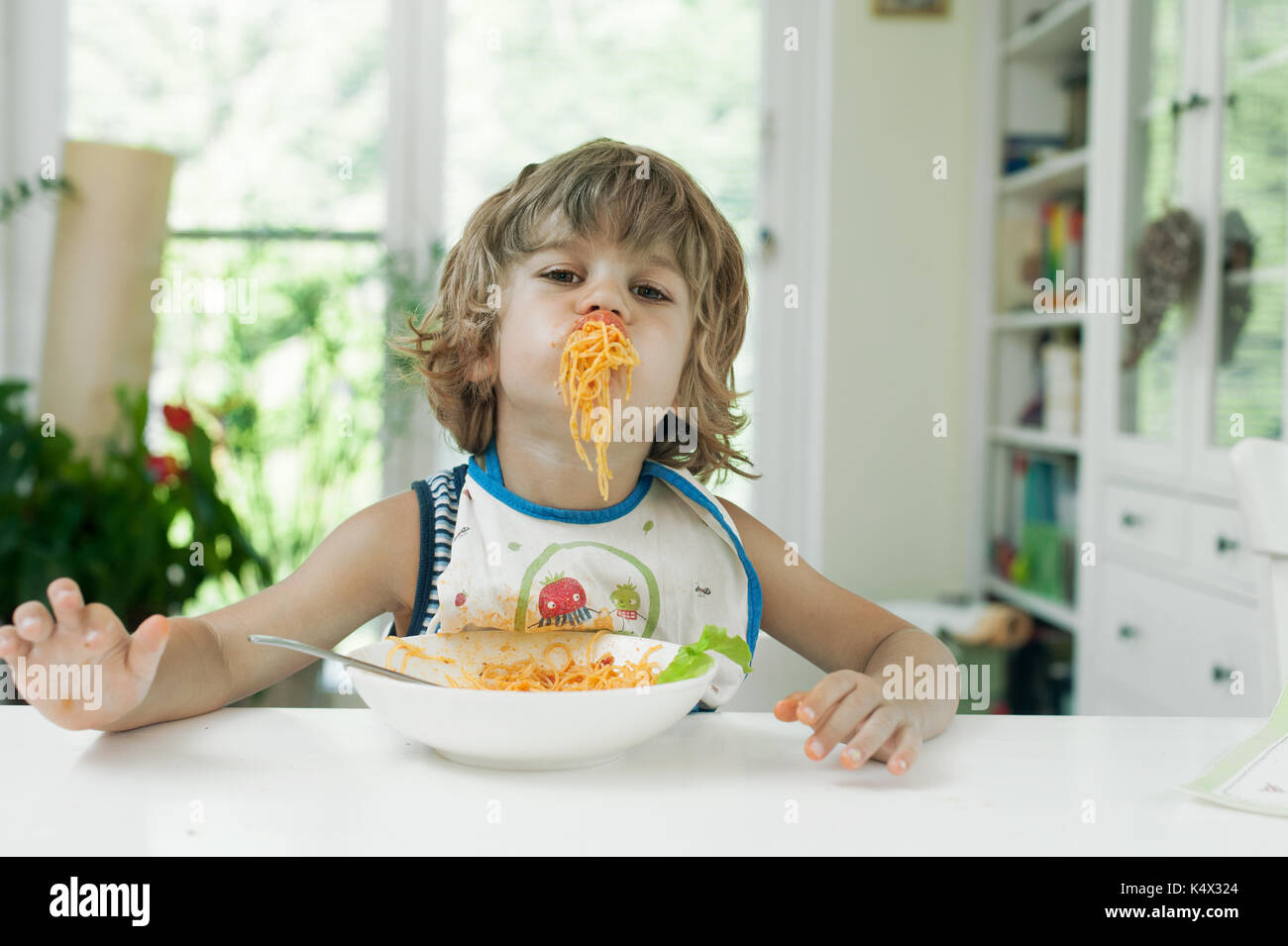 Ritratto di un simpatico ragazzo facendo un pasticcio mentre mangi la pasta per il pranzo Foto Stock