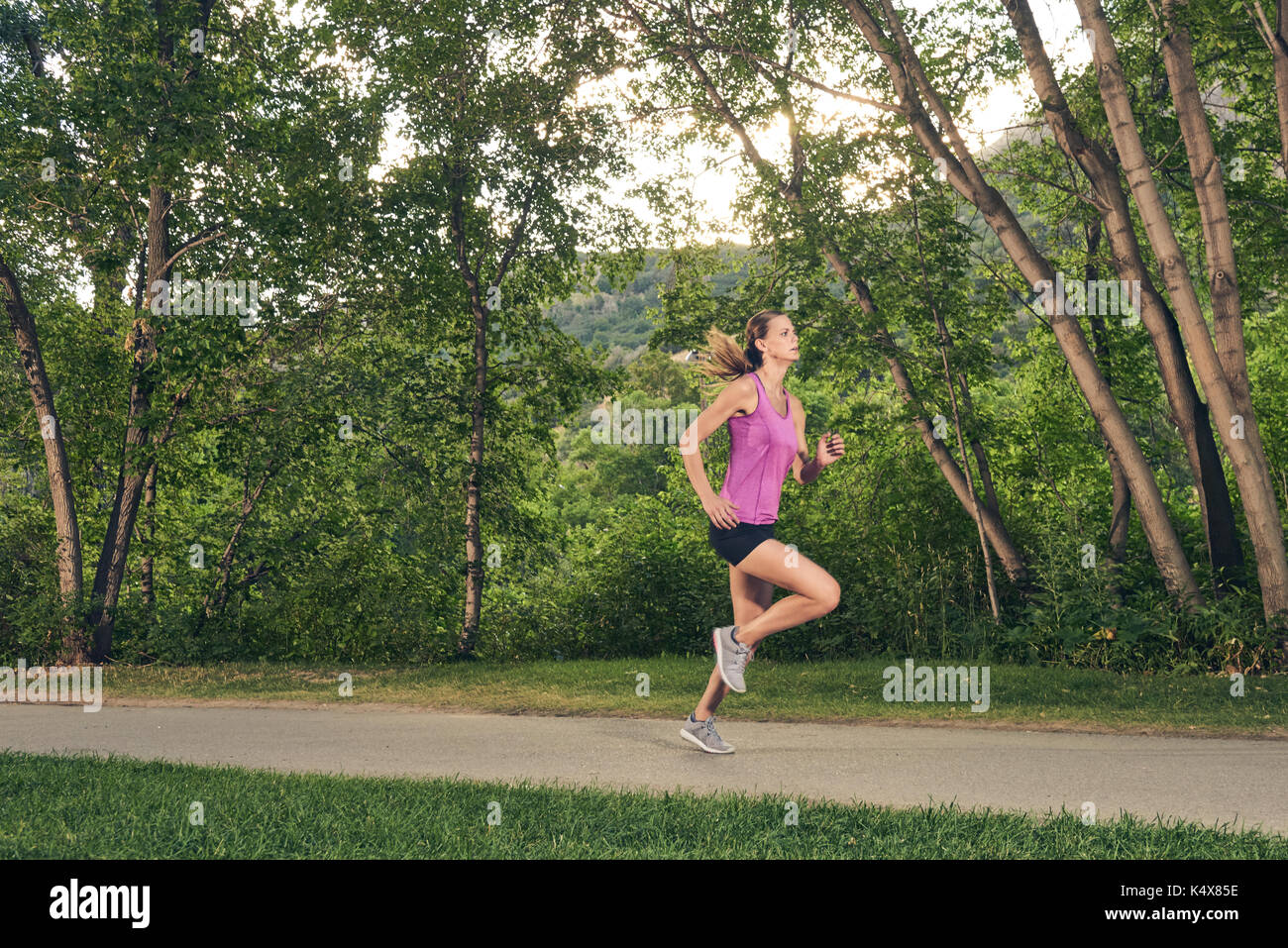 La donna in esecuzione attraverso il parco sul percorso di corsa Foto Stock