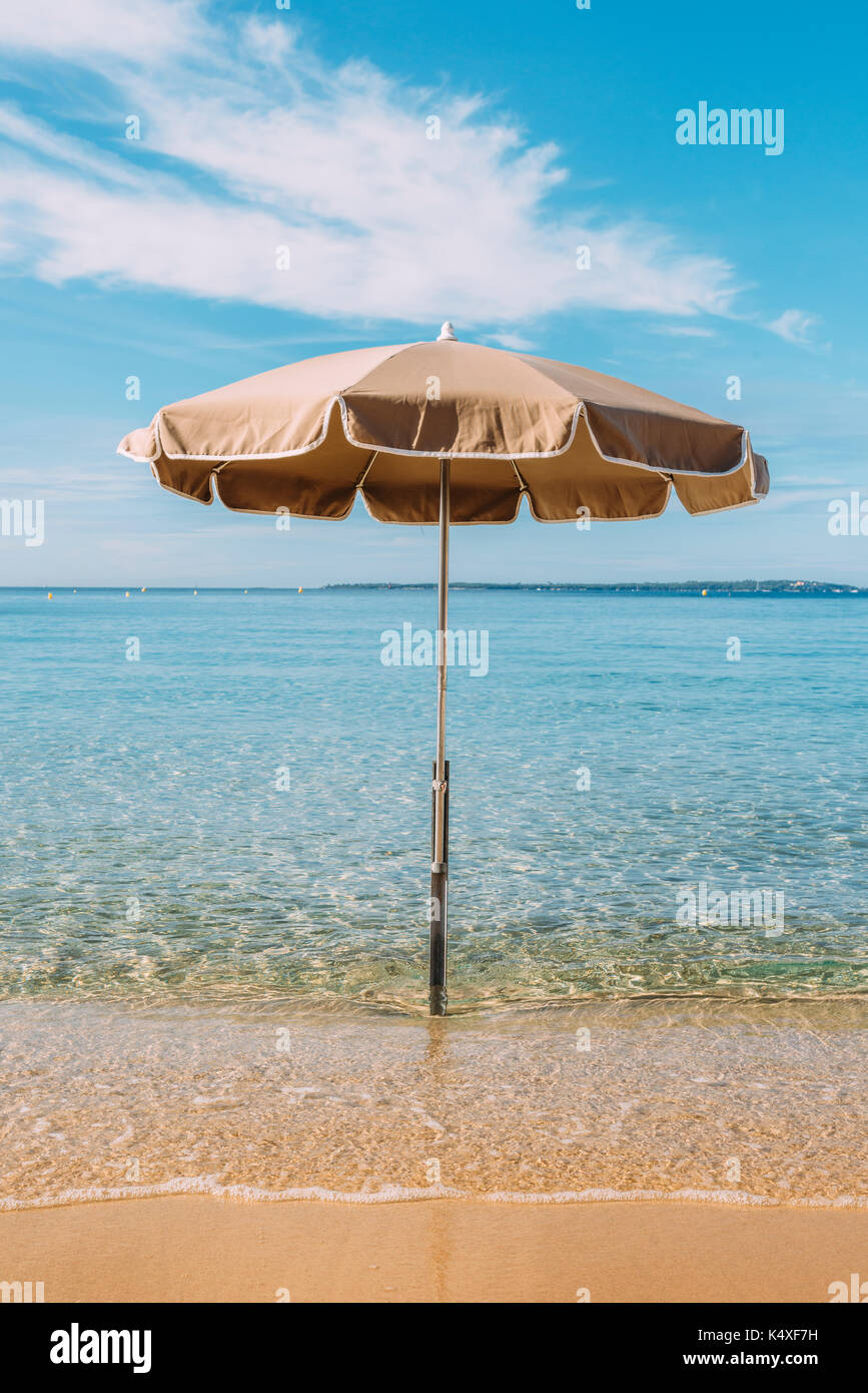 Un ombrellone in acqua su una spiaggia tropicale con un cielo blu Foto Stock