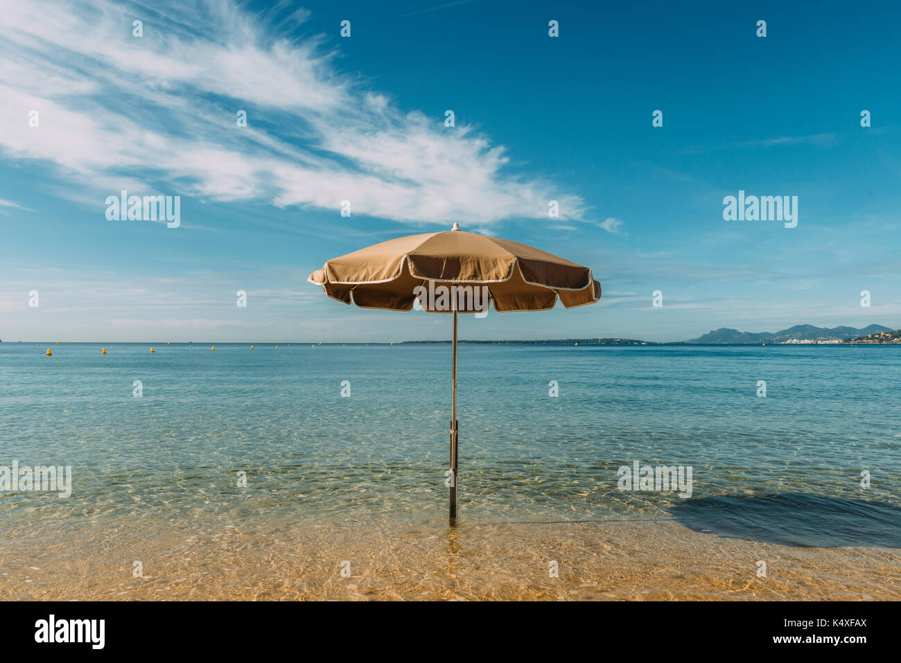 Un ombrellone in acqua su una spiaggia tropicale con un cielo blu Foto Stock