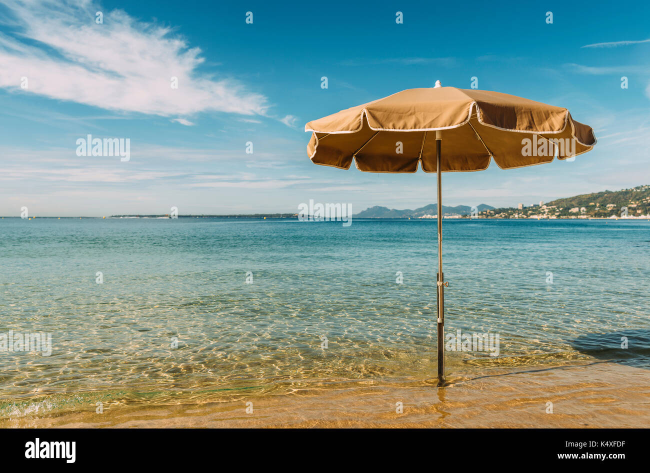 Un ombrellone in acqua su una spiaggia tropicale con un cielo blu Foto Stock