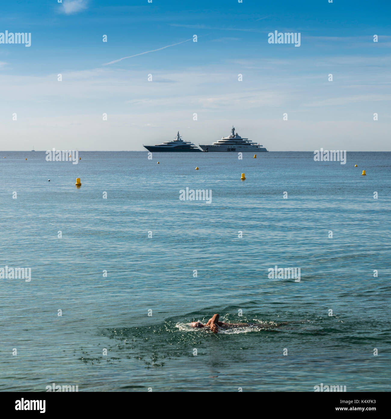 Lone nuotatore con yacht di lusso in background Foto Stock
