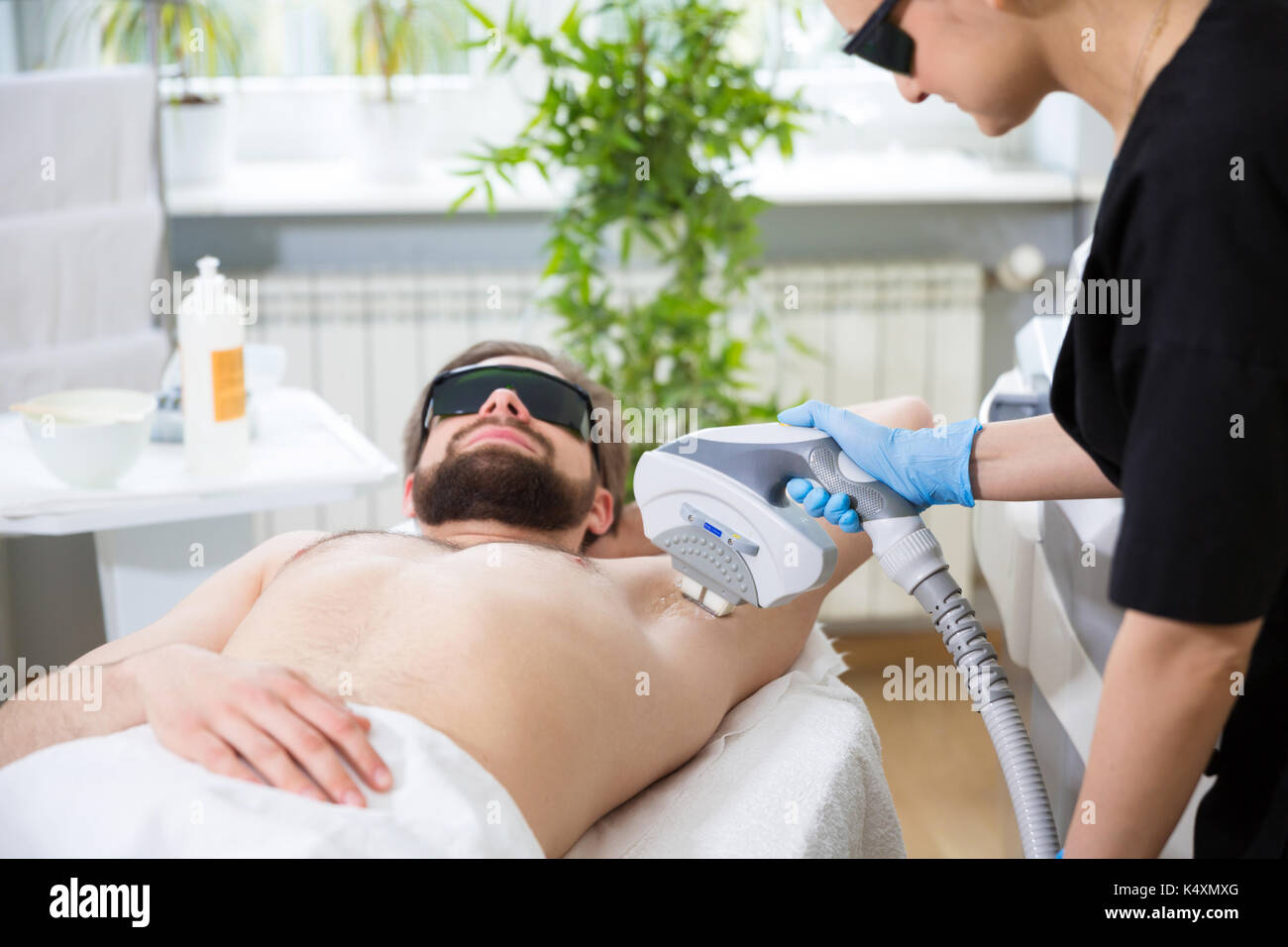 Gli uomini che giace a estetista durante il laser ascelle Depilazione terapia Foto Stock