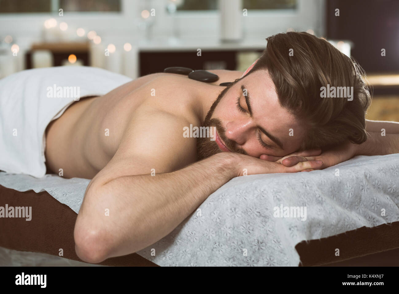 Uomo relax nella spa al massaggio hot stone Foto Stock