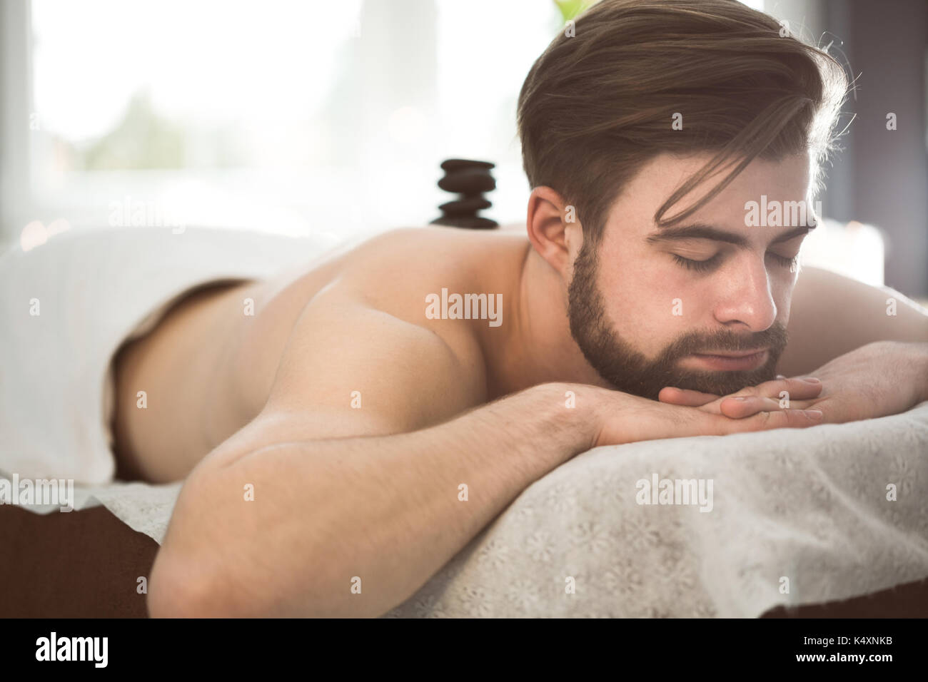 Uomo relax nella spa al massaggio hot stone Foto Stock