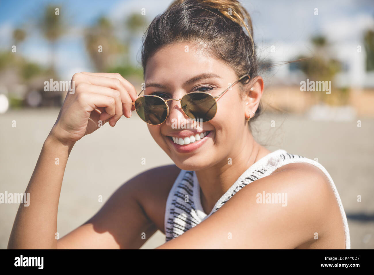 Close up ritratto di giovane donna graziosa azienda occhiali da sole sorridente Foto Stock