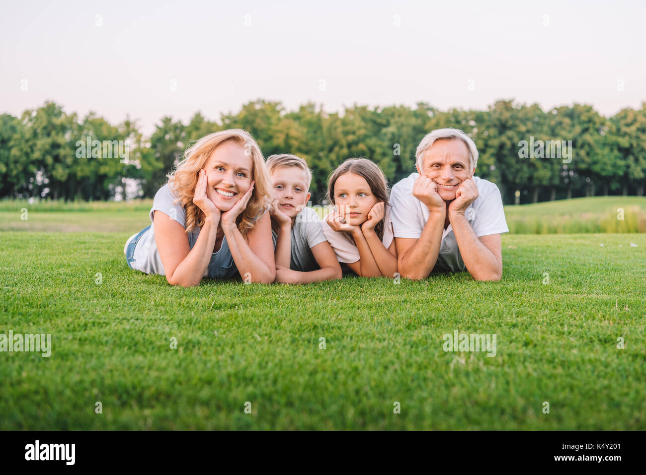 Allegro nonni e nipoti poco giacente insieme sul prato Foto Stock