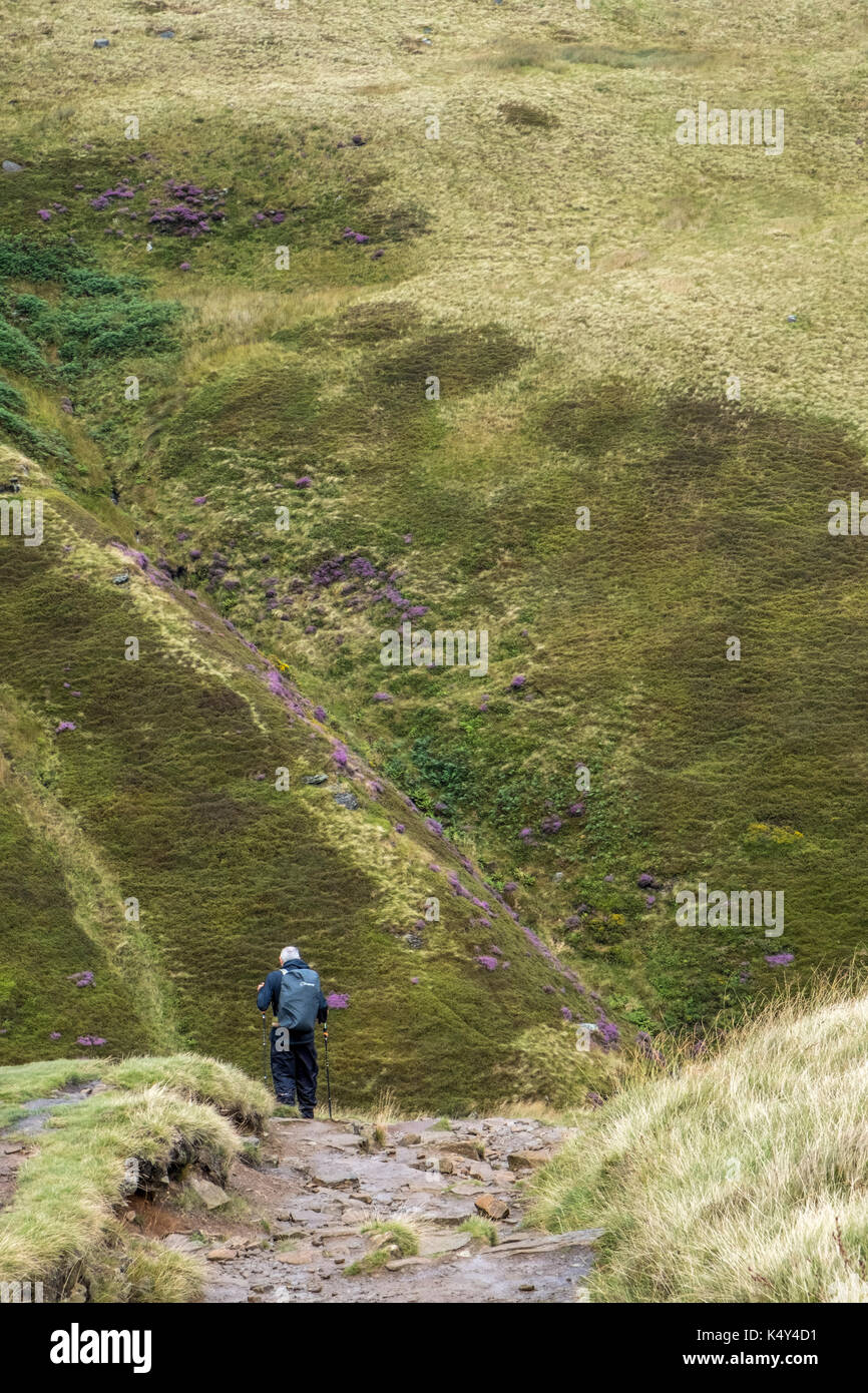 Passeggiate in collina. Walker scendendo la scala di Giacobbe visto contro la collina di Kinder Scout, Derbyshire, Peak District, England, Regno Unito Foto Stock