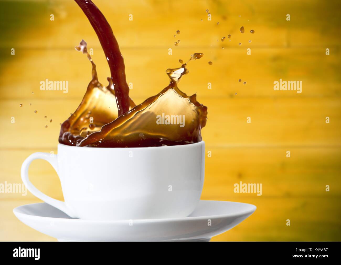 Composito Digitale del caffè è versata nella tazza bianca contro sfocata giallo pannello di legno Foto Stock