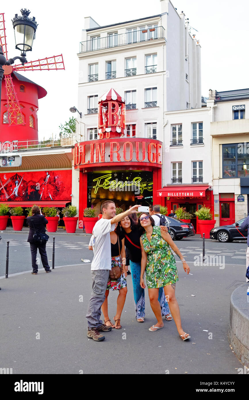 I turisti posano per una selfie foto di gruppo n davanti al Moulin Rouge Cabaret club a Pigalle, vicino a Montmartre a Parigi Foto Stock