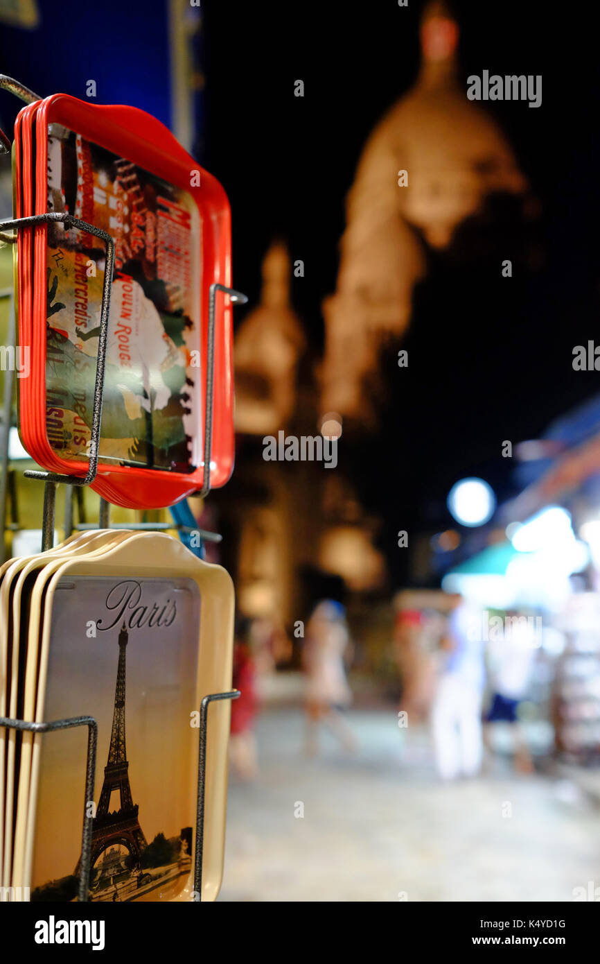 Souvenir turistici sulla vendita di notte in Montmartre, Parigi con il Sacre Coeur in background Foto Stock
