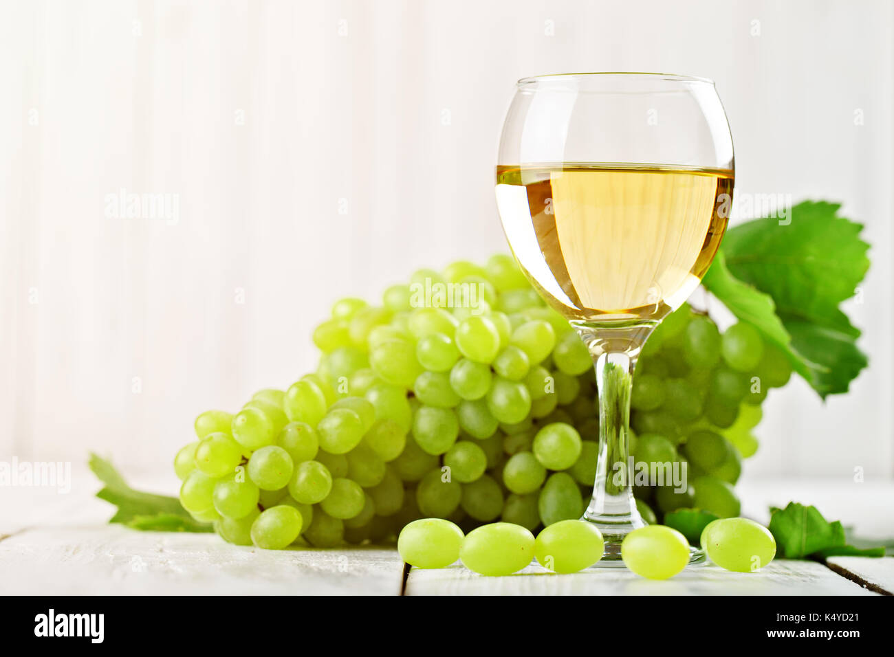 Un bicchiere di vino bianco e uva fresca su un tavolo di legno. Foto Stock