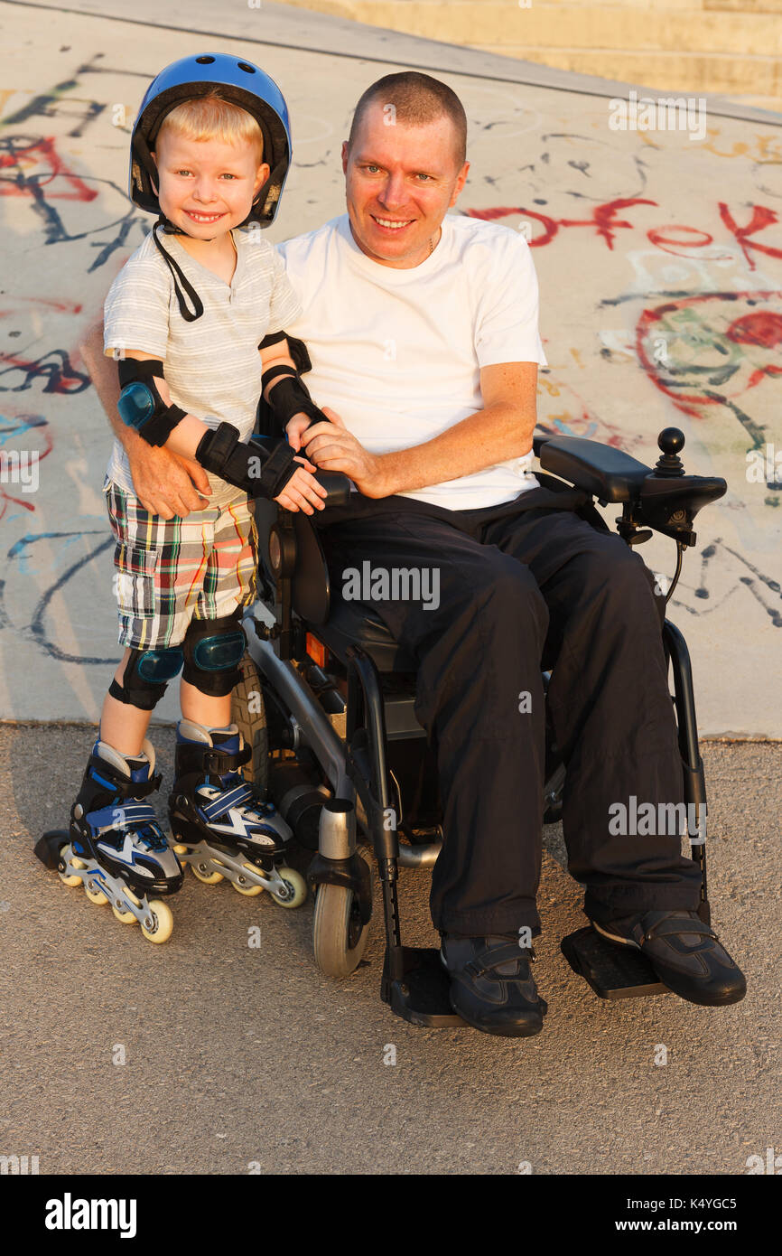 Padre disabili roller con piccolo figlio Foto Stock