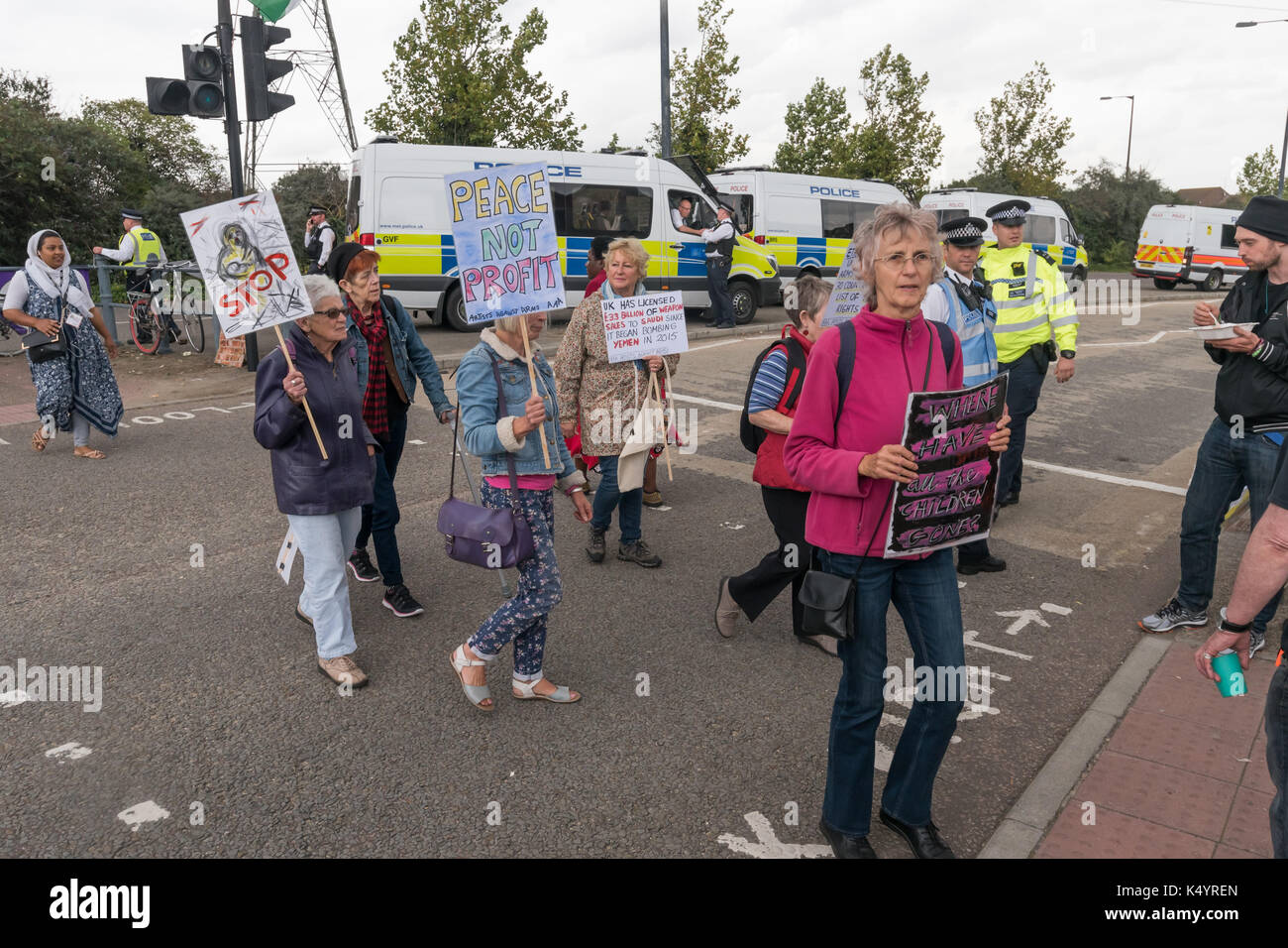 Londra, Regno Unito. Il 7 settembre 2017. I manifestanti a piedi attraversata la strada con cartelli e manifesti alla fermata della Fiera di bracci di protesta al di fuori del centro di ExCeL in cui sono in corso i preparativi per il mondo la più grande fiera di armi, DSEI, la difesa e le attrezzature di sicurezza internazionale, sostenuta dal governo del Regno Unito in cui le società di armi e i commercianti di armi vendere armi ai paesi di tutto il mondo tra cui molti regimi repressivi. Credito: Peter Marshall / Alamy Live News Foto Stock