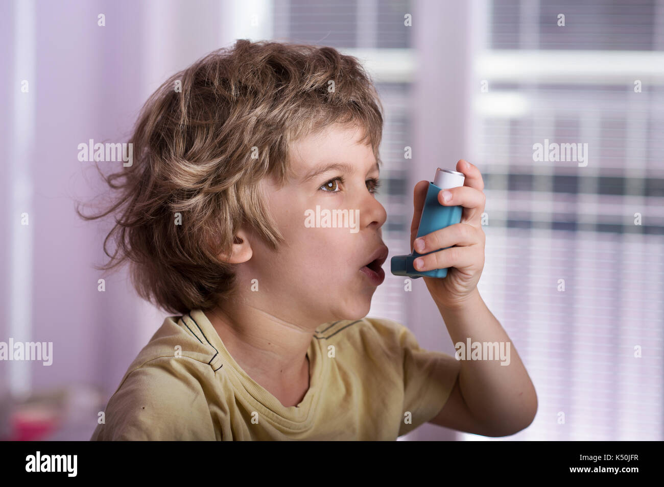 Boy utilizzando l'asma inalatore per trattare malattie infiammatorie, dispnea, tosse e di tenuta al torace e mancanza di respiro. allergia al concetto di trattamento. Foto Stock