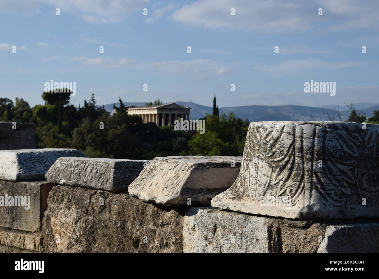 Parete con la colonna di marmo frammenti con ornamenti intagliati all'antica agorà di Atene in Grecia. il tempio di Efesto può essere visto in background Foto Stock