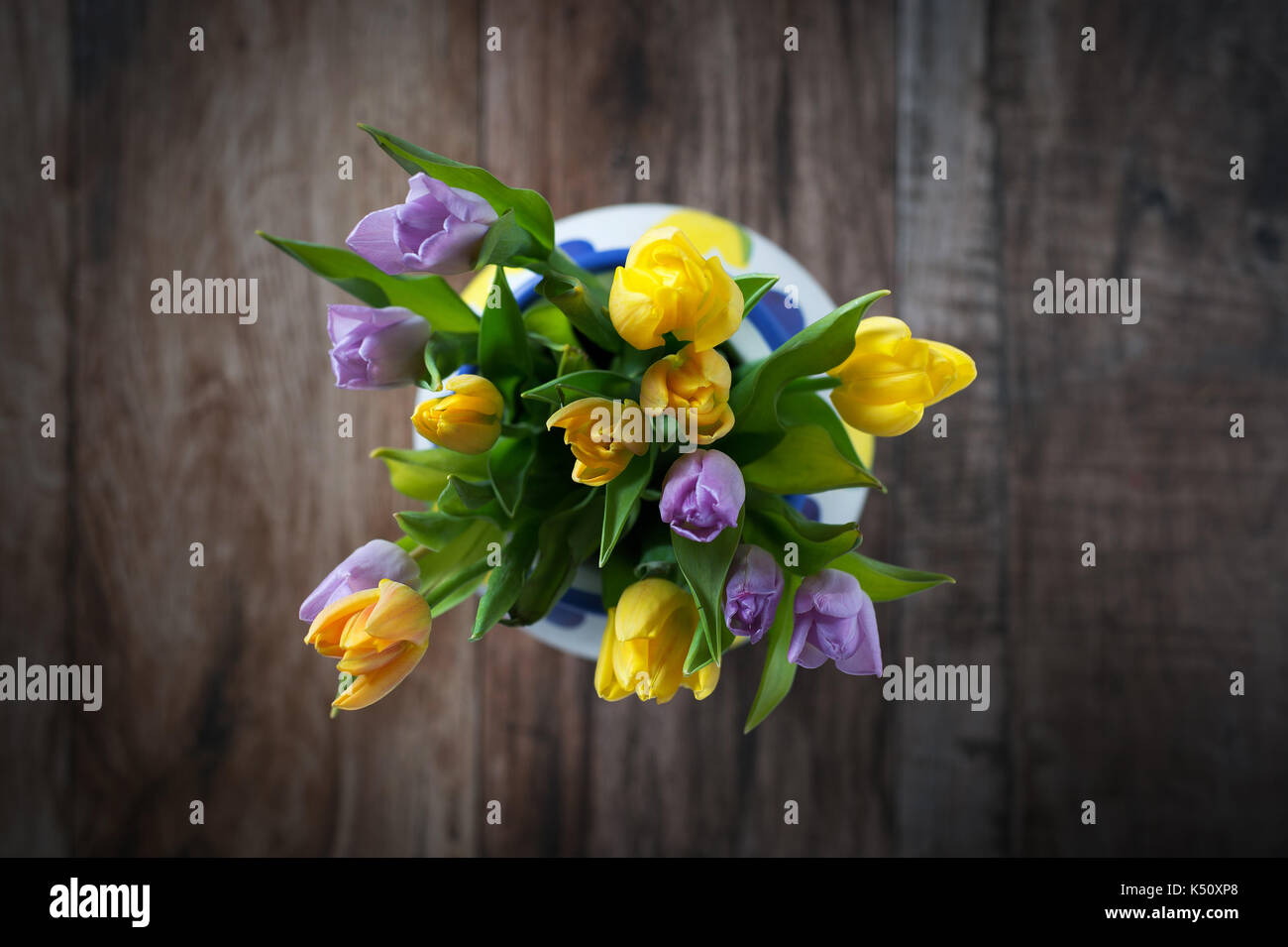 Bouquet di tulipani in vaso ripresa dall'alto. home decor interno su tavola in legno rustico. La primavera è qui concetto. Foto Stock