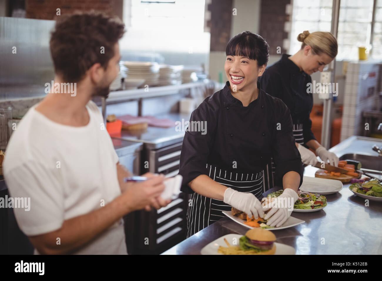 Allegro cameriere e femmina di lavoro dello chef in cucina presso il cafe Foto Stock