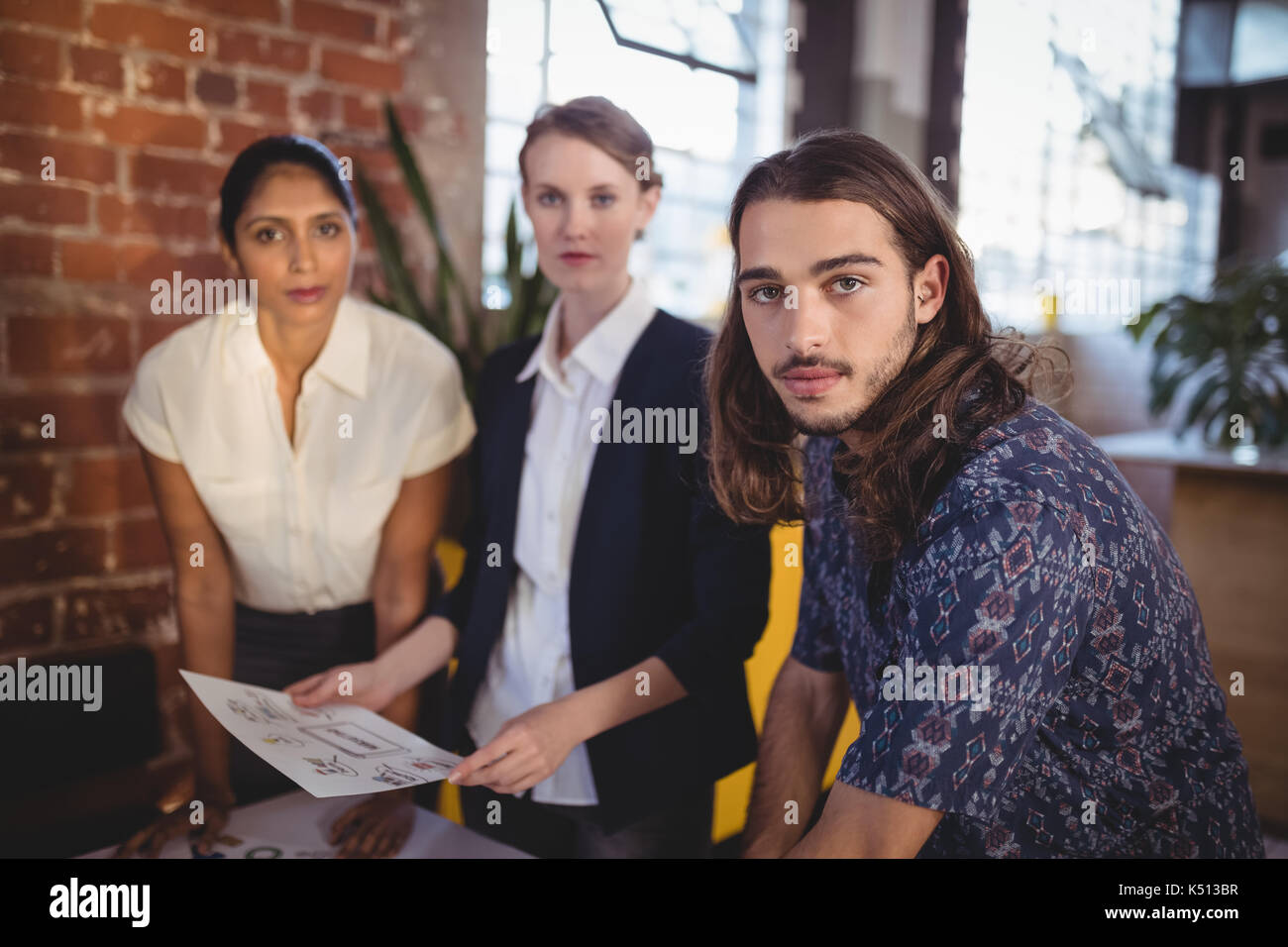 Ritratto di giovane fiducioso team creativo in piedi con i documenti presso la caffetteria Foto Stock