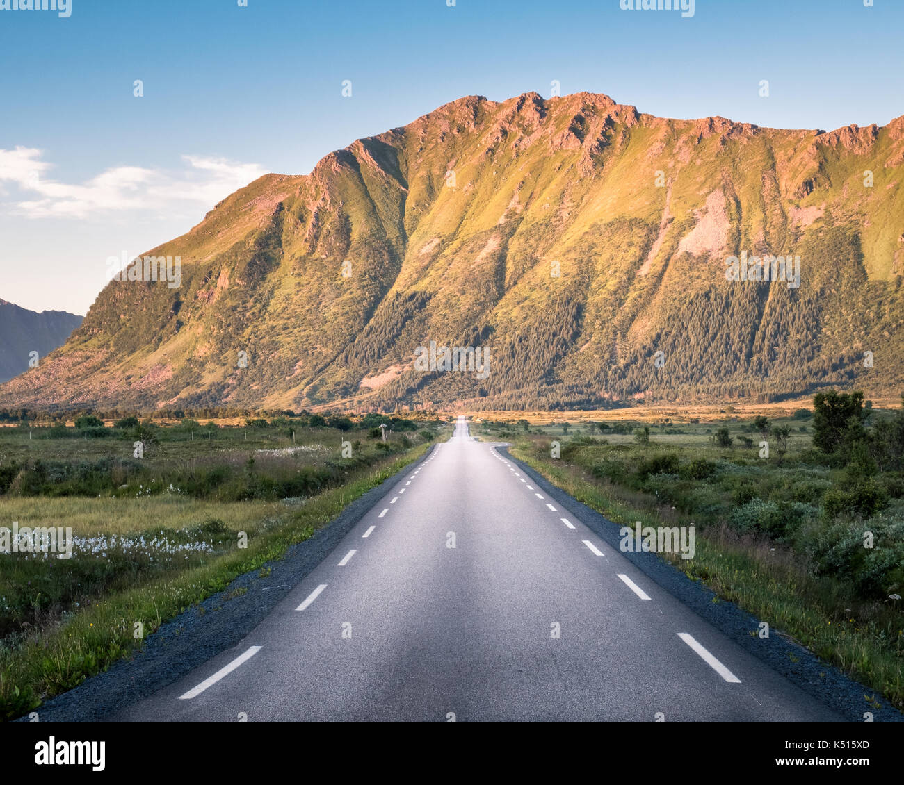 Dritto su strada asfaltata con paesaggio montano contro il cielo blu in Lofoten, Norvegia Foto Stock