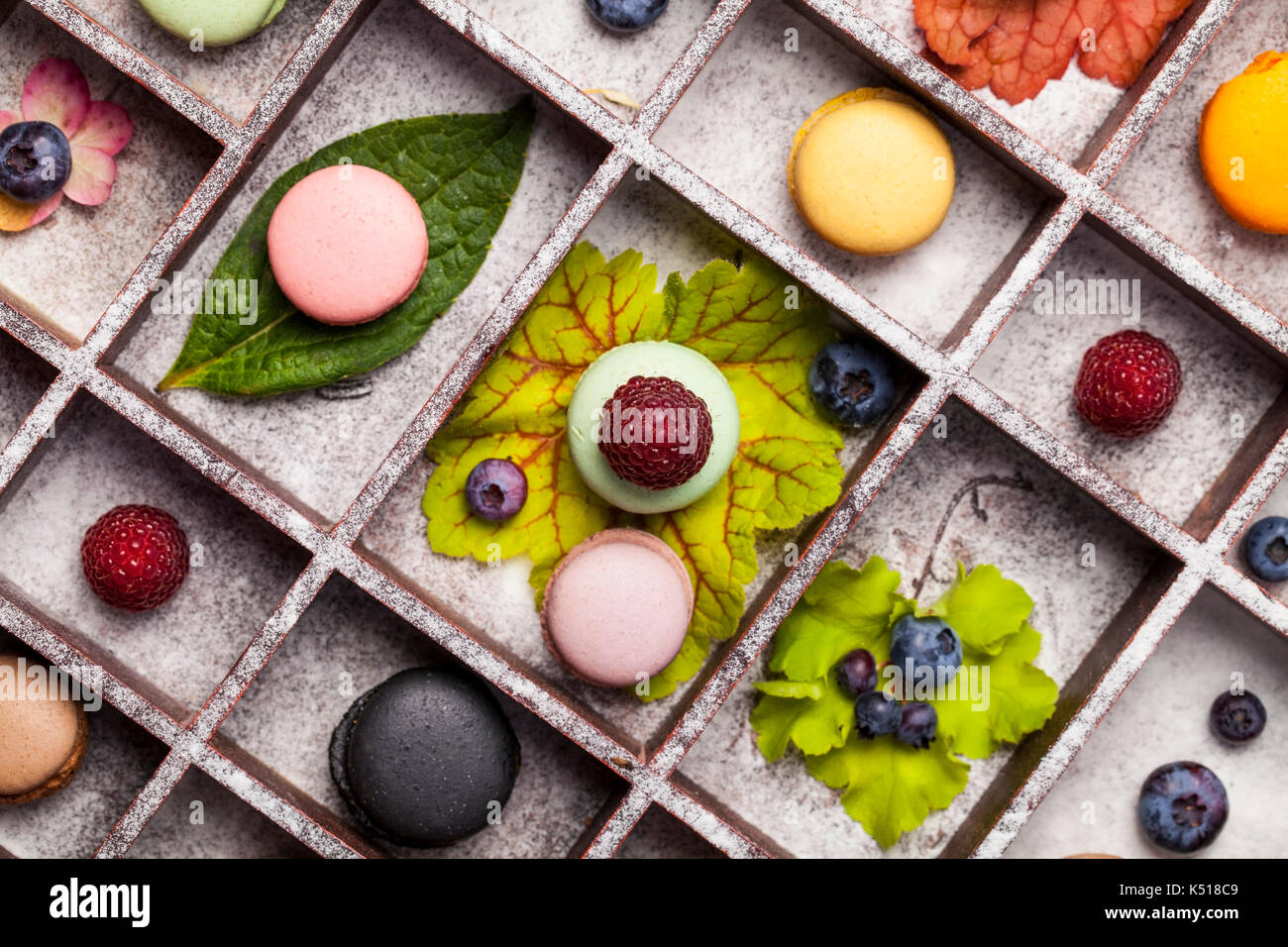 Varietà di coloratissimi dolce francese dessert - makaron ( les macarons) con fiori autunnali e bacche. Foto Stock